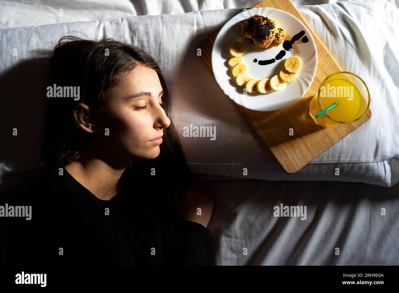 Frau schläft mit Frühstück im Bett. Stockfoto
