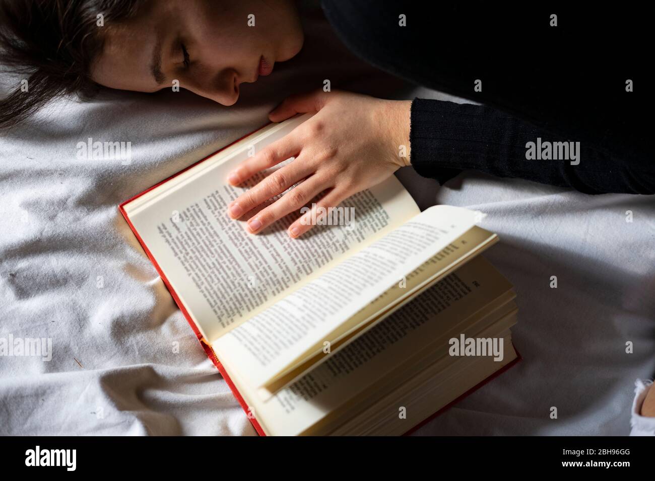 Frau schläft neben einem offenen Buch. Stockfoto