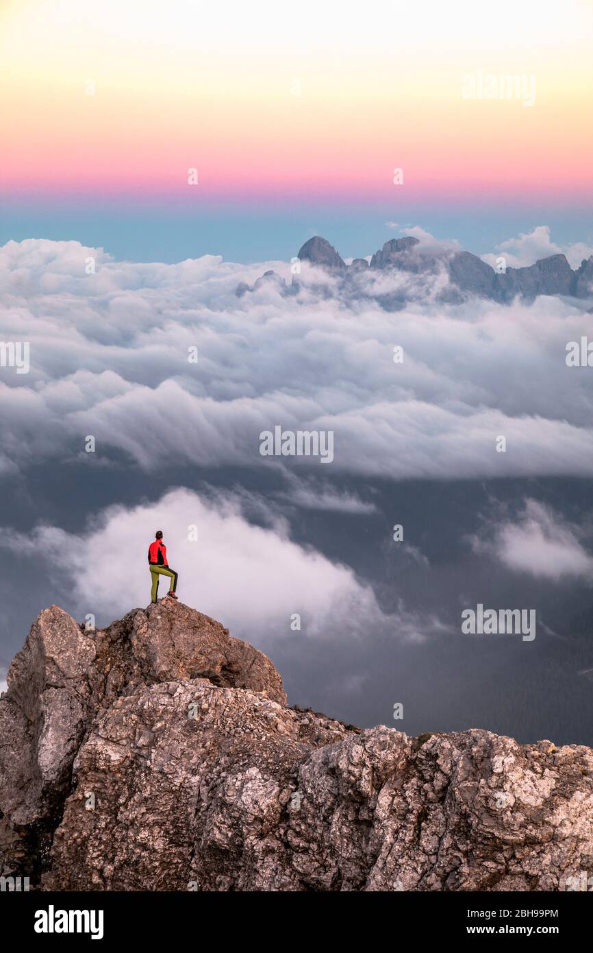 Einsamer Mann steht auf einem Bergrücken, im Hintergrund ein Wolkenmeer rund um die Agner Bergkette, Pale di San Martino Gruppe, Blick vom Costabella-Grat, Dolomiten, Italien Stockfoto