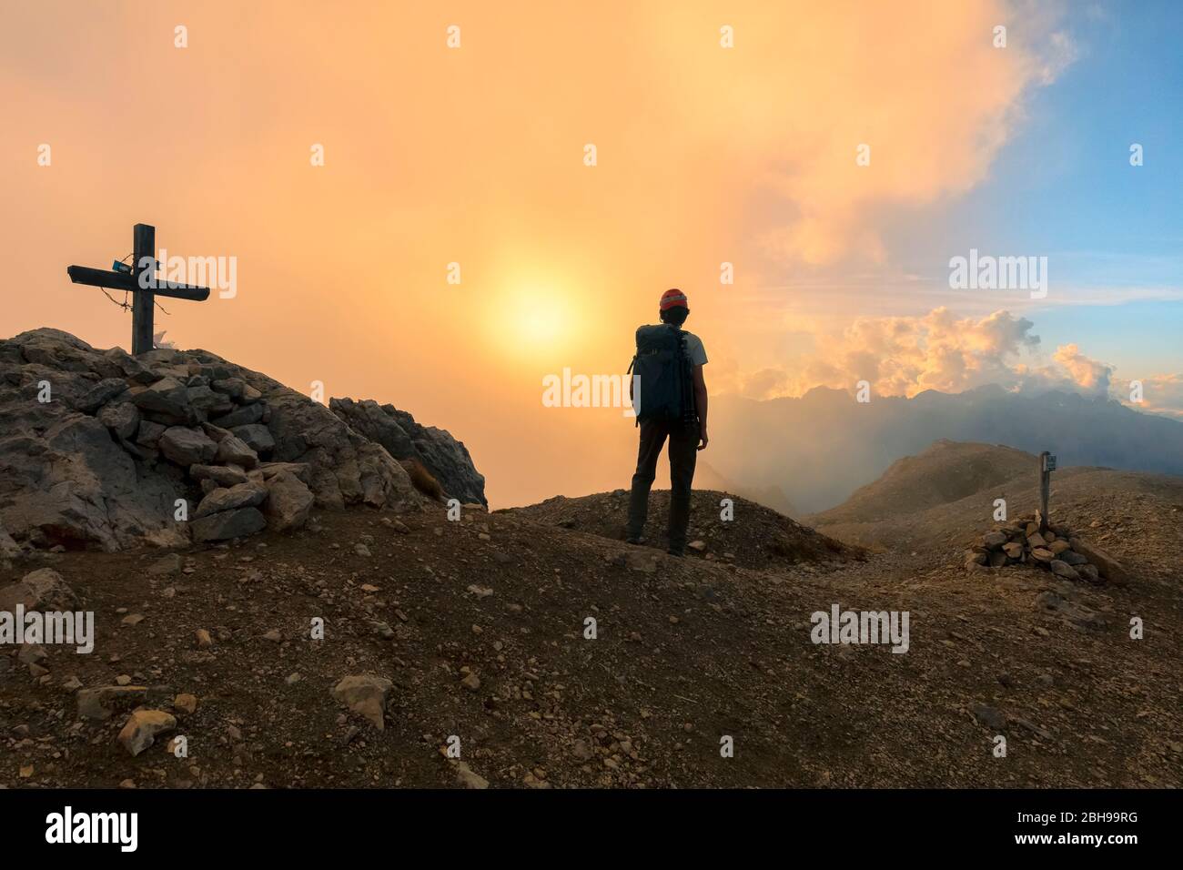 Ein Wanderer übersteht einen wolkigen Sonnenuntergang vom Gipfel der Cima Campagnaccia, Costabella Ridge, Marmolada-Gruppe, Dolomiten, Moena, Fassatal, Trient Provinz, Trentino-Südtirol, Italien. Stockfoto