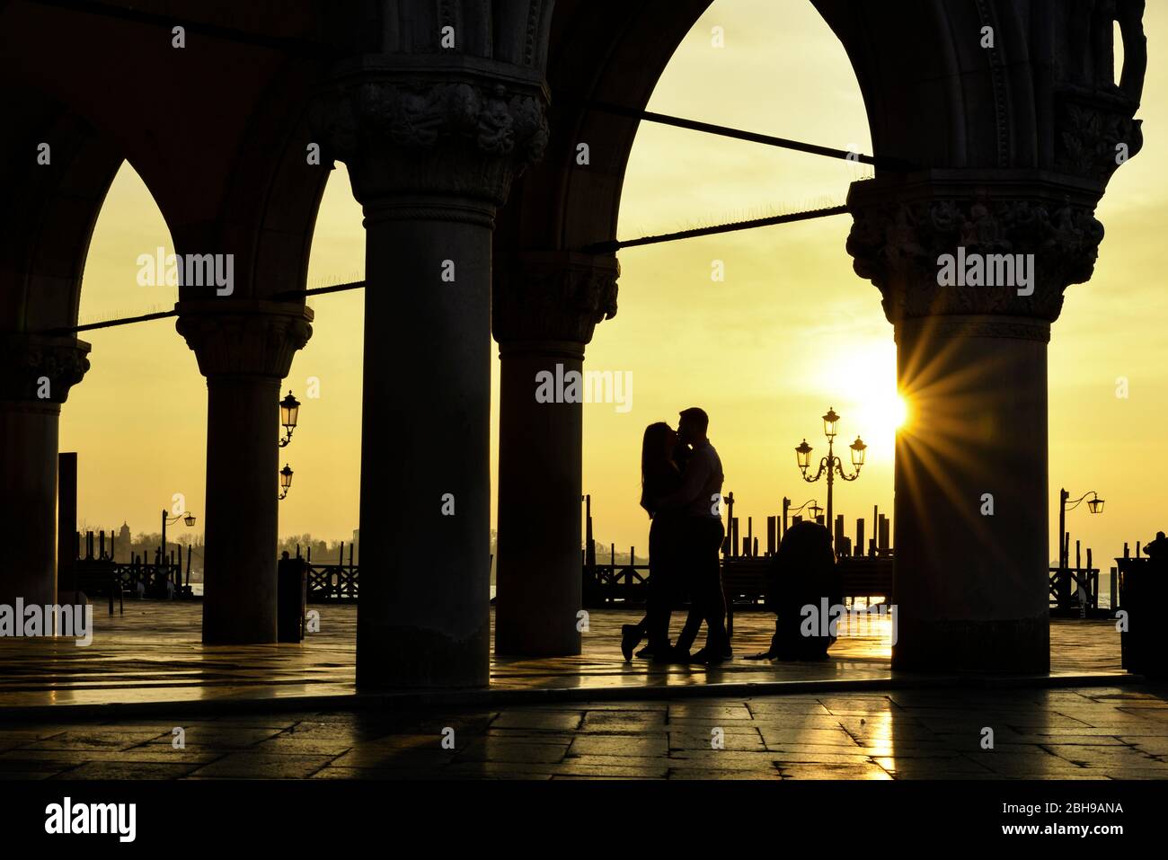 Silhouette eines küssenden romantischen Paares im Dogenpalast in Venedig bei Sonnenaufgang an einem nassen Wintermorgen Stockfoto