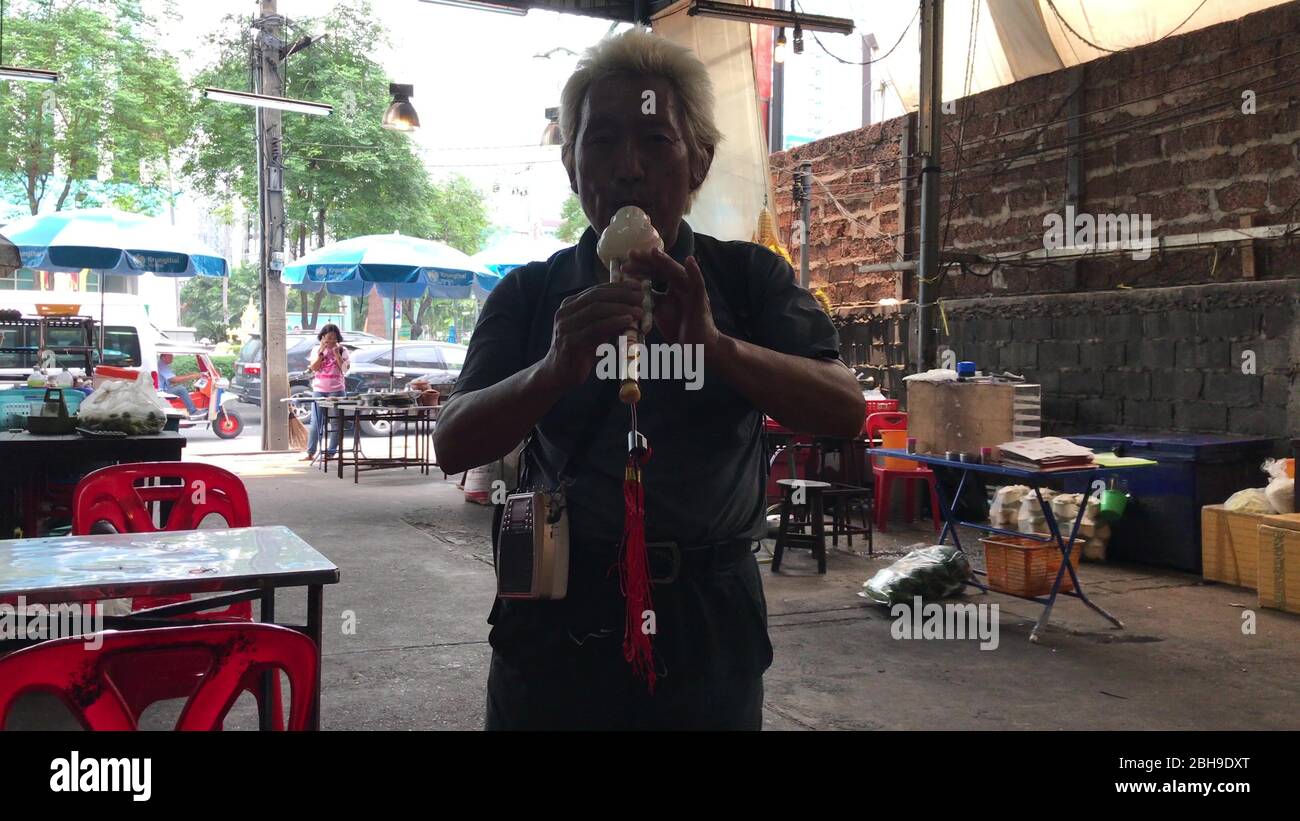 KO CHANG, THAILAND - 9. APRIL 2018: Mann auf einer billigen Restaurantterrasse, der Flöte spielt Stockfoto