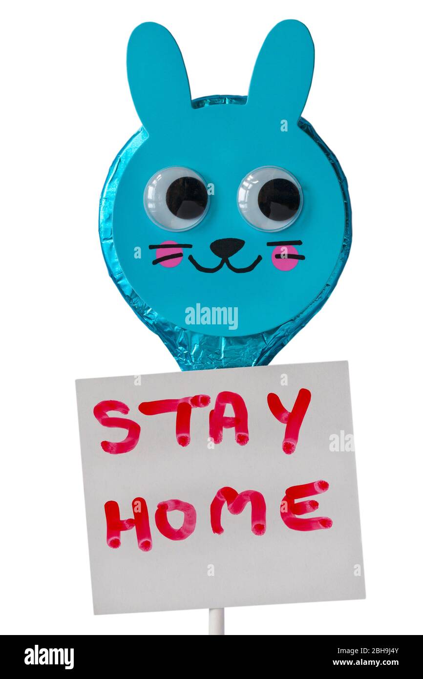 M&S Osterhase folierte Vollmilchschokolade-Lollipop mit Stay Home-Schild auf weißem Hintergrund - Konzept, um zu Hause zu bleiben für Coronavirus Sperrung UK Stockfoto