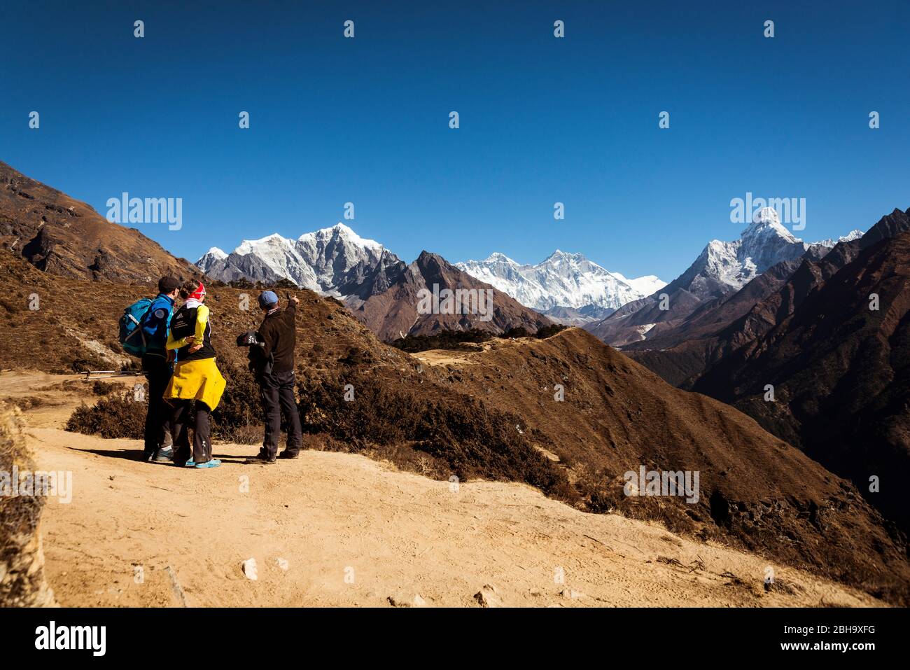 3 Wanderer von hinten am Wegrand stehend, Ama Dablam, Himalaya, Landschaft, Stockfoto