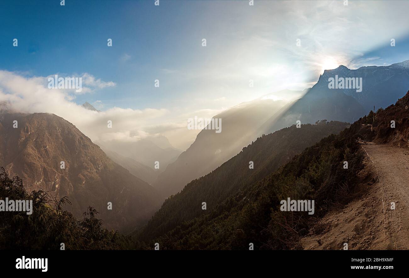 Unterwegs, später Nachmittag, Blick ins Tal, Himmel mit Wolken, Sonne verschwindet hinter den Bergen, Stockfoto