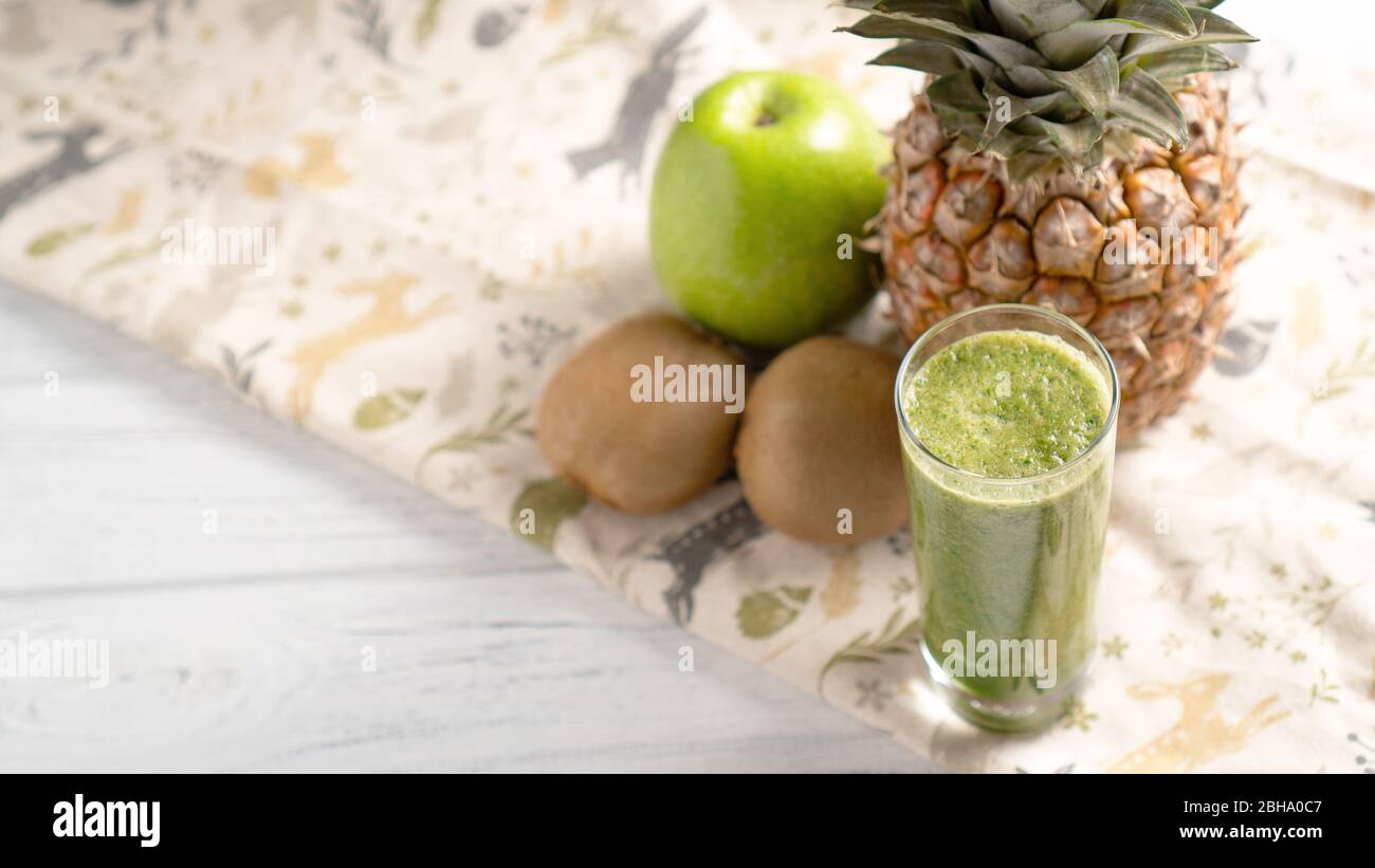 Beschütze dein Herz. Grüner Kiwi Apfel Ananas Smoothie im Glas mit Früchten auf Hintergrund mit Platz für Text. Stockfoto