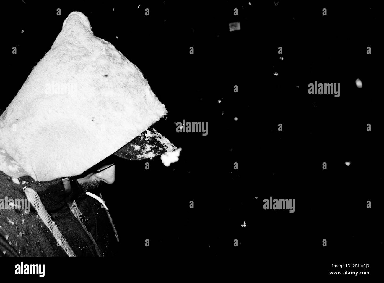 Mann mit Kapuze und Schneeflocken, seitlich, Nahaufnahme, nachts Stockfoto
