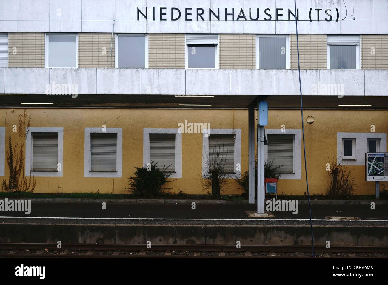 Ein leeres Bahnhofsgebäude des Bahnhofs Niedernhausen mit vergitterten Fenstern und Klinkerfassade. Stockfoto