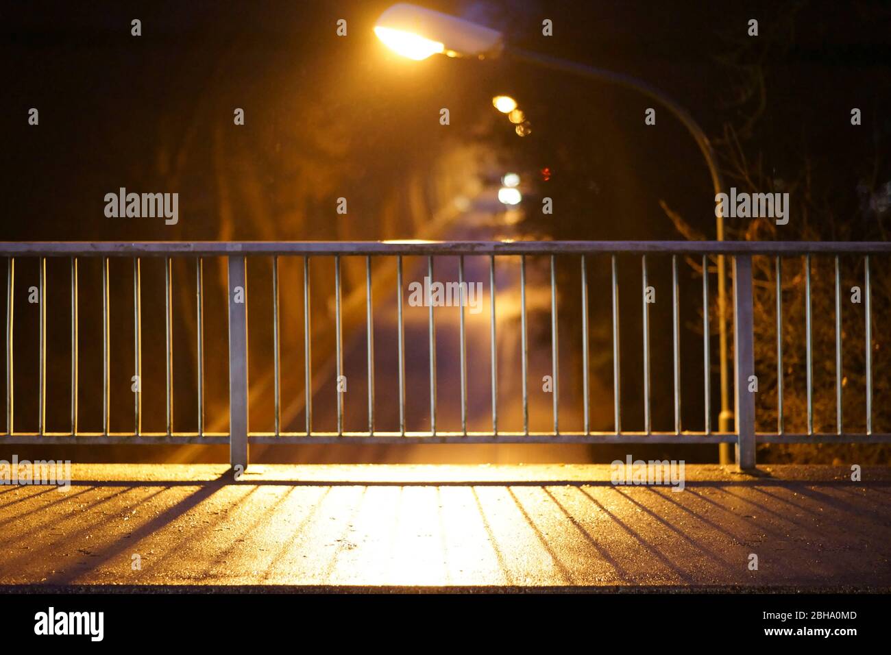 Die Nahaufnahme eines Laufes einer Brücke am Abend, deren Geländer symmetrische Schatten werfen. Stockfoto