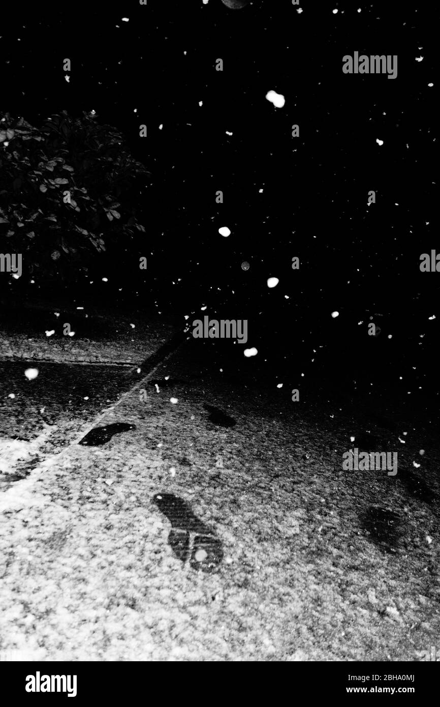 Schneeflocken und Fußspuren in der Nacht Stockfoto