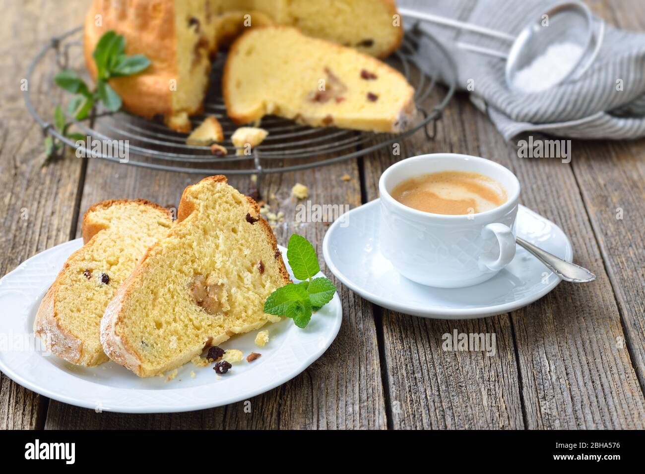 Frischer österreichischer Heferingkuchen mit Mandelpaste und Rosinen, sogenannter Gugelhupf, serviert mit einer Tasse köstlichem Kaffee Crema Stockfoto