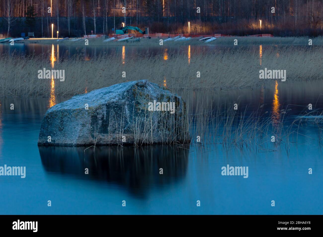 Ein isolierter Felsen in ruhigem Wasser in finnischer Dämmerung Stockfoto