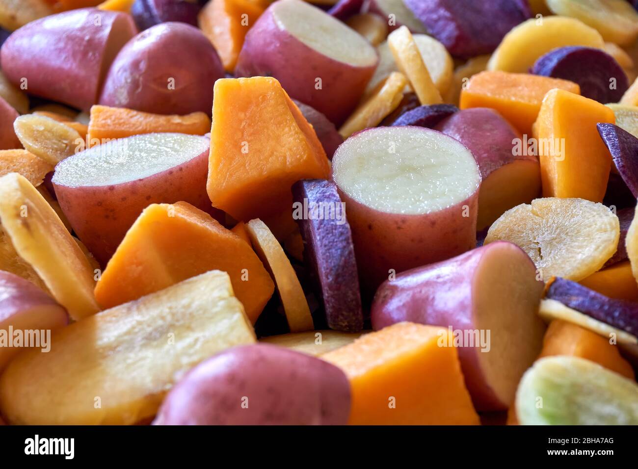 Gehackte Kartoffeln, Kürbisse und orange, gelbe und lila Karotten. Flacher Einschnitt von frisch geschnittenem Gemüse in verschiedenen Farben. Gesundes Essen Konzept. Stockfoto