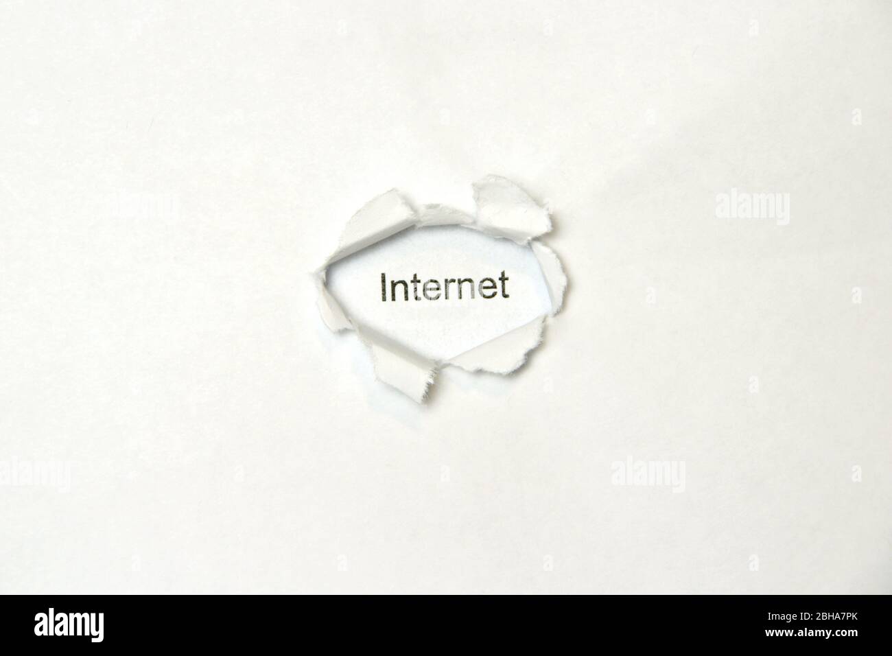 Wort Internet auf weißem, isoliertem Hintergrund, die Inschrift durch das Wundloch im Papier. Stock Foto für Web und Print mit leerem Raum für Text und Design. Stockfoto