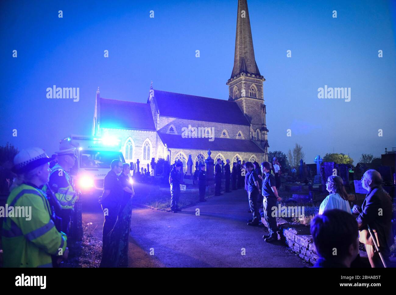 Swansea, Wales, Großbritannien. April 2020. Die Mitarbeiter des Rettungsdienstes stehen zu Ehren in einer Wache, die von einer Flut von blauem Licht aus ihren Fahrzeugen überflutet wird, während eines Gedenkens für den Rettungsdienst Gerallt Davies, der letzte Woche an Covid-19 gestorben ist. Die Mitarbeiter, viele, die mit Gerallt arbeiteten, wurden mit Mitgliedern seiner Gemeinde aus dem Dorf Pontadardawe in der Nähe von Swansea verbunden. Er war das erste Mitglied des Welsh Ambulance Services NHS Trust, das mit Covid-19 starb, so sein Chief Executive. Quelle : Robert Melen/Alamy Live News. Stockfoto