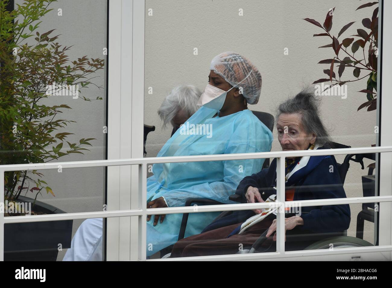 Krankenschwester Pflege für ältere Menschen in einem Pflegeheim während der Coronavirus-Pandemie Covid-19. Betreuerin mit zwei alten Frauen, die dort wohnen. Stockfoto