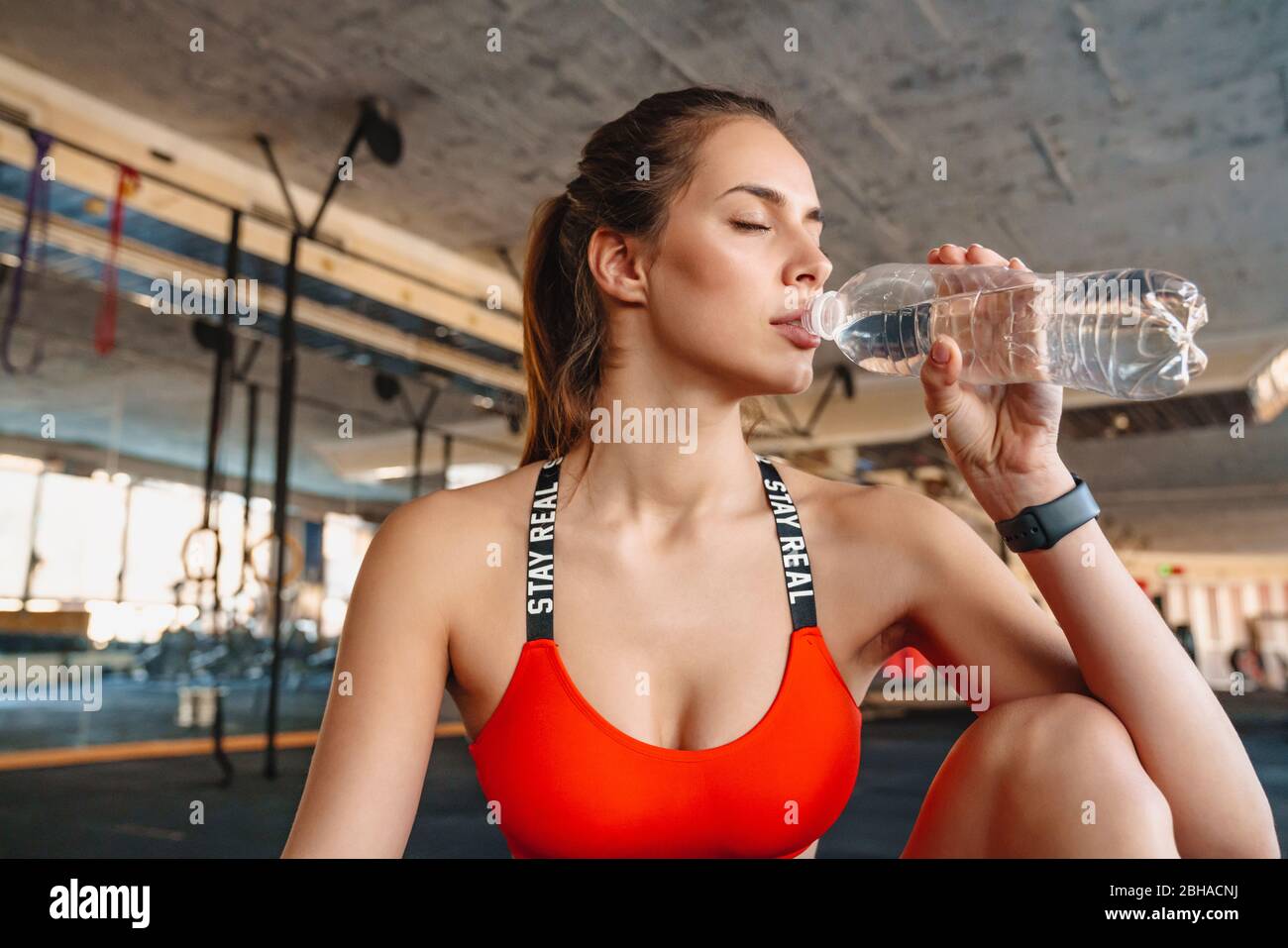 Attraktive gesunde junge Sportlerin Trinkwasser aus einer Flasche während des Trainings im Fitnessstudio Stockfoto