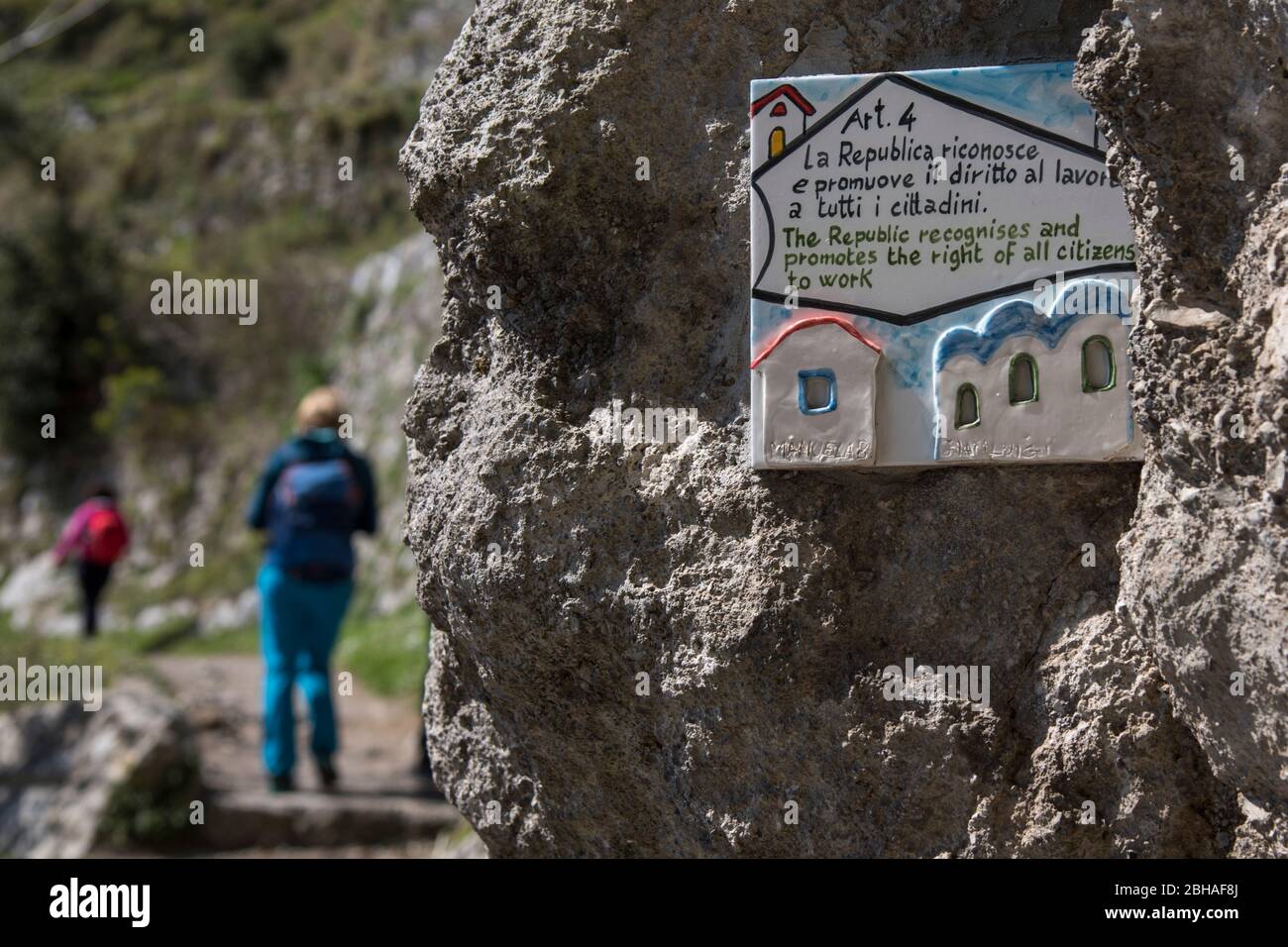 Der Weg der Götter: Sentiero degli Dei. Unglaublich schöner Wanderweg hoch über der Amalfitana oder Amalfi Küste in Italien, von Agerola nach Positano. März 2019. "Recht aller Bürger auf Arbeit": mit Botschaft unterschreiben. 2 Wanderer, Rückansicht Stockfoto