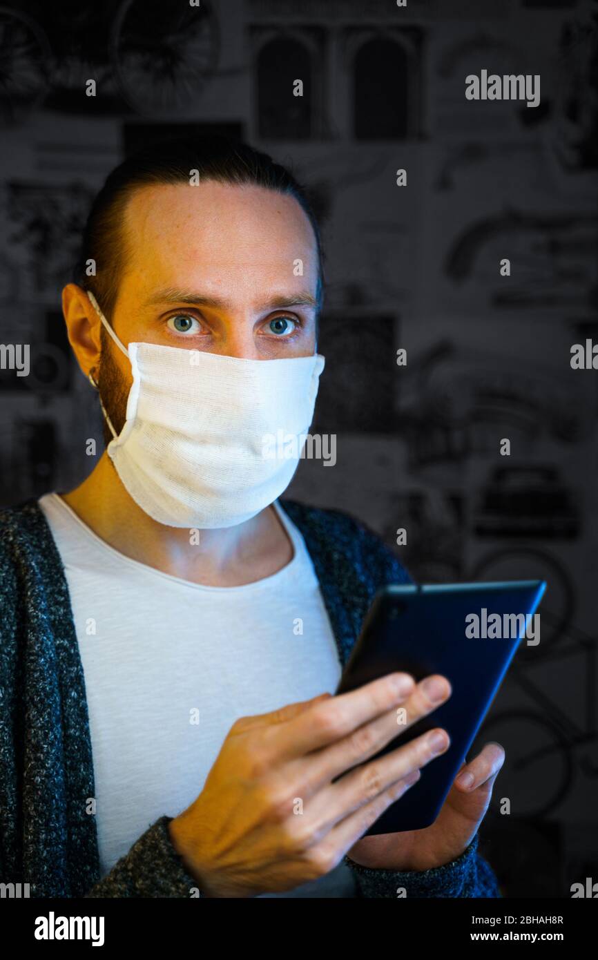 Porträt eines bärtigen Mannes mit einer Tafel in den Händen in einer Gaze-Maske. Vorbeugender Schutz Ihrer eigenen Gesundheit vor Virusinfektionen. Stockfoto
