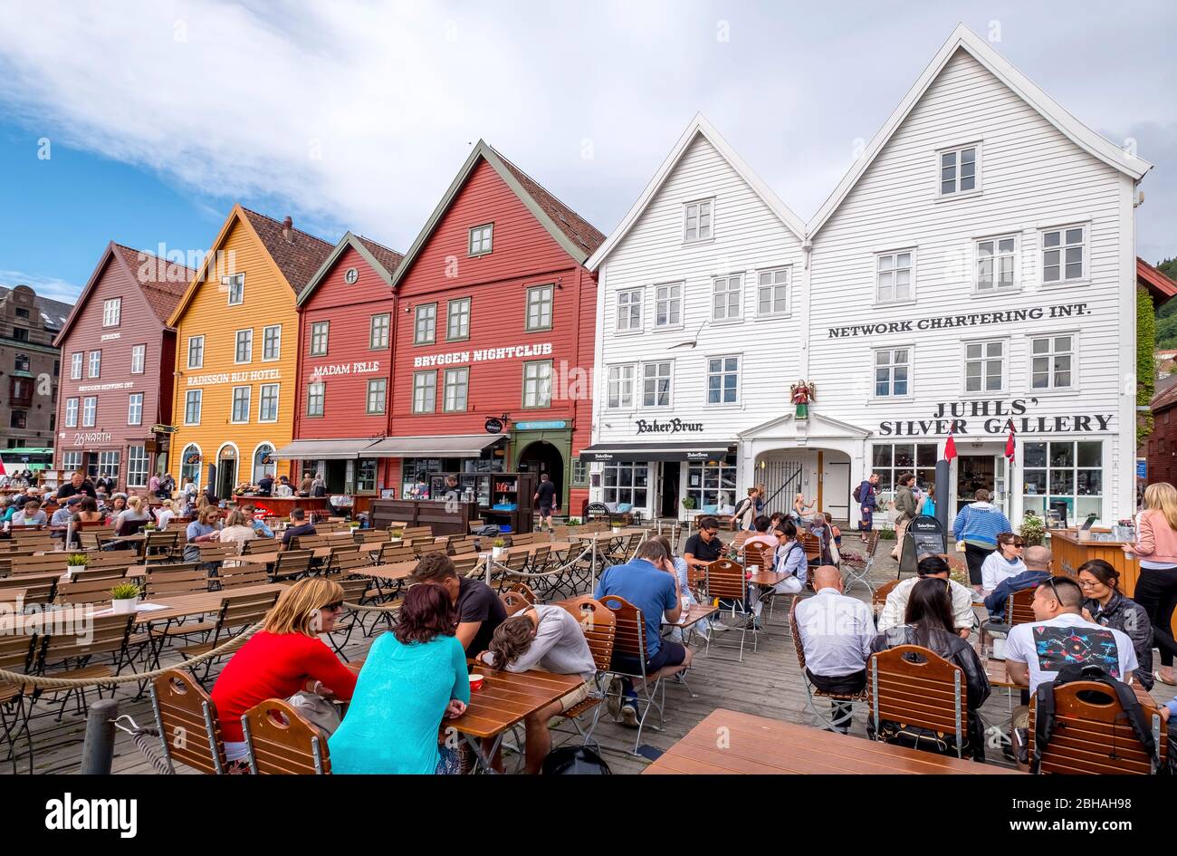 Touristen sitzen an Tischen vor der historischen Kulisse der bunten Holzhäuser in Bryggen im Hanseviertel Bryggen, Torget, der Deutschen Werft, Bergen, Hordaland, Norwegen, Skandinavien, Europa Stockfoto