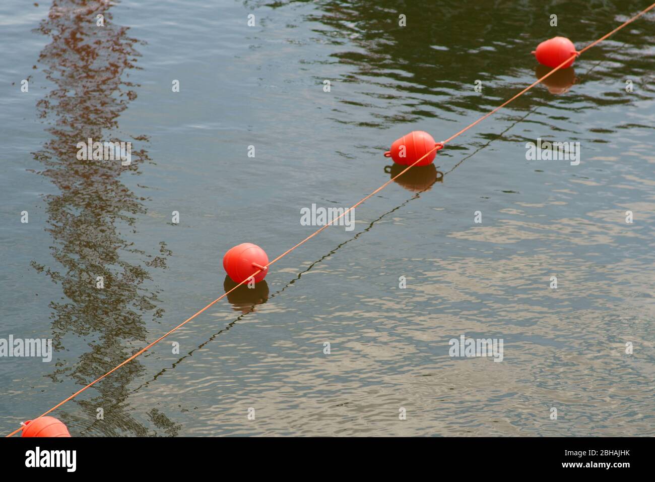 Ein gestrecktes Seil mit nebeneinander angeeinandergereisten schwimmenden Bojen, um einen Wasserzugang im Binnenhafen abzusperren. Stockfoto