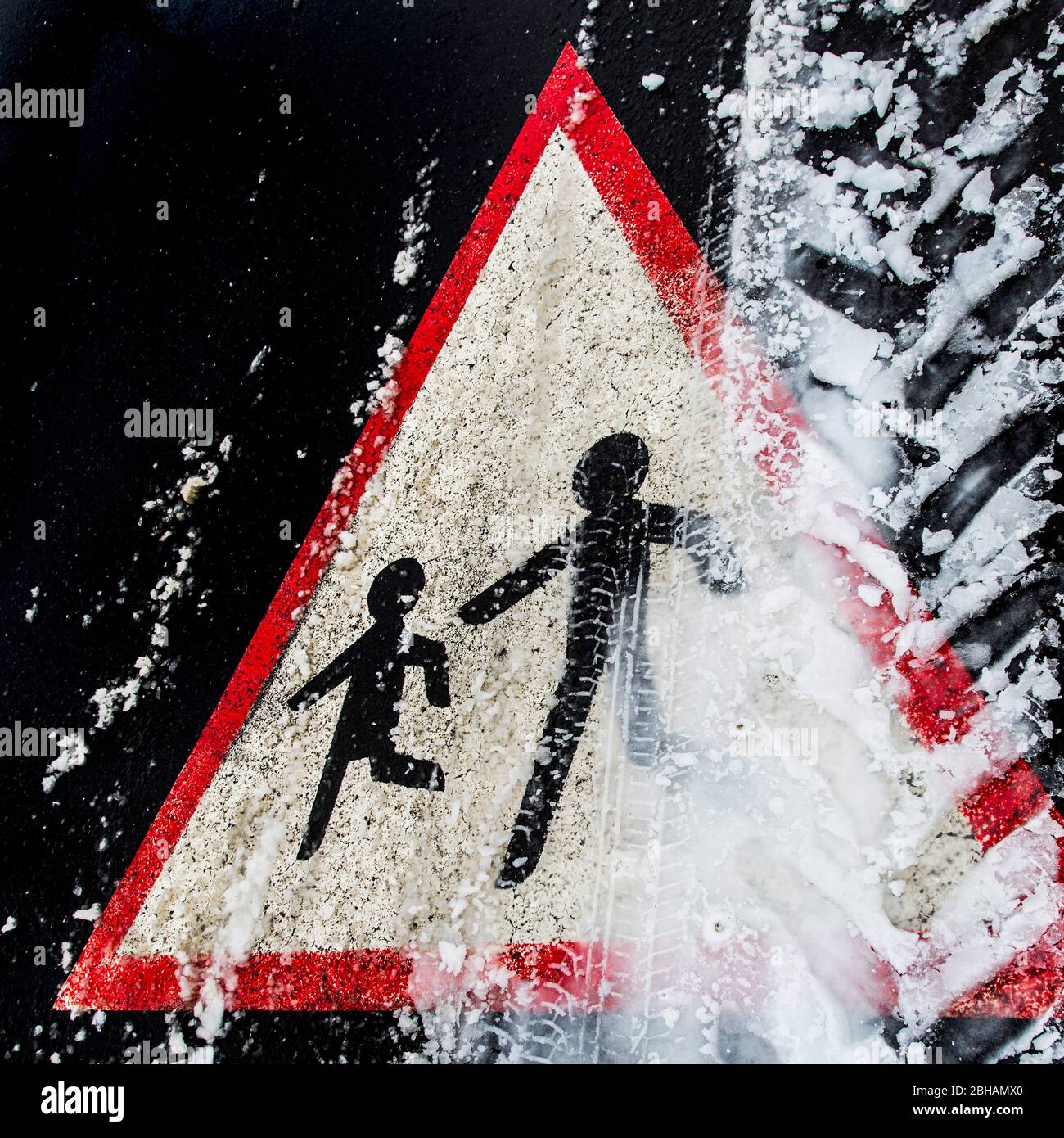 Vorsicht: Spielende Kinder mit Reifenspuren im Schnee Stockfoto