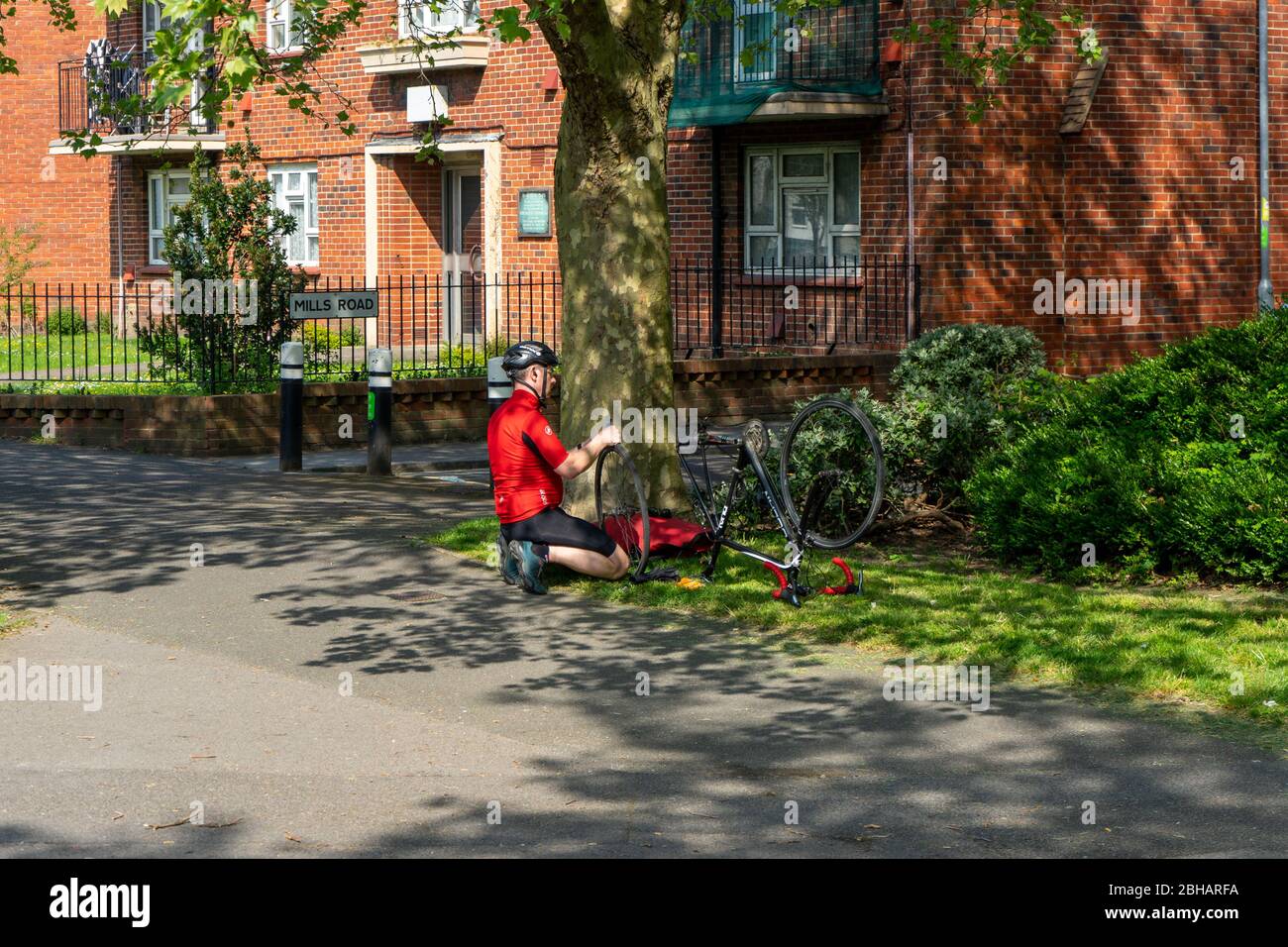 Ein Radfahrer repariert sein Fahrrad am Straßenrand, nachdem er einen Reifenschaden bekommen hat Stockfoto