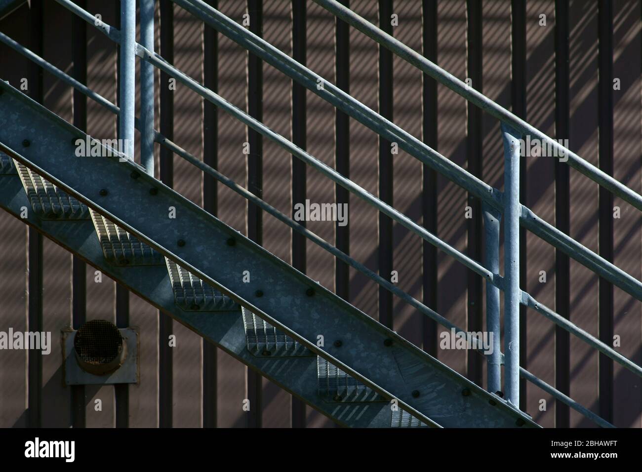 Die Nahaufnahme der Außentreppe eines Industriegebäudes, das Schatten wirft. Stockfoto