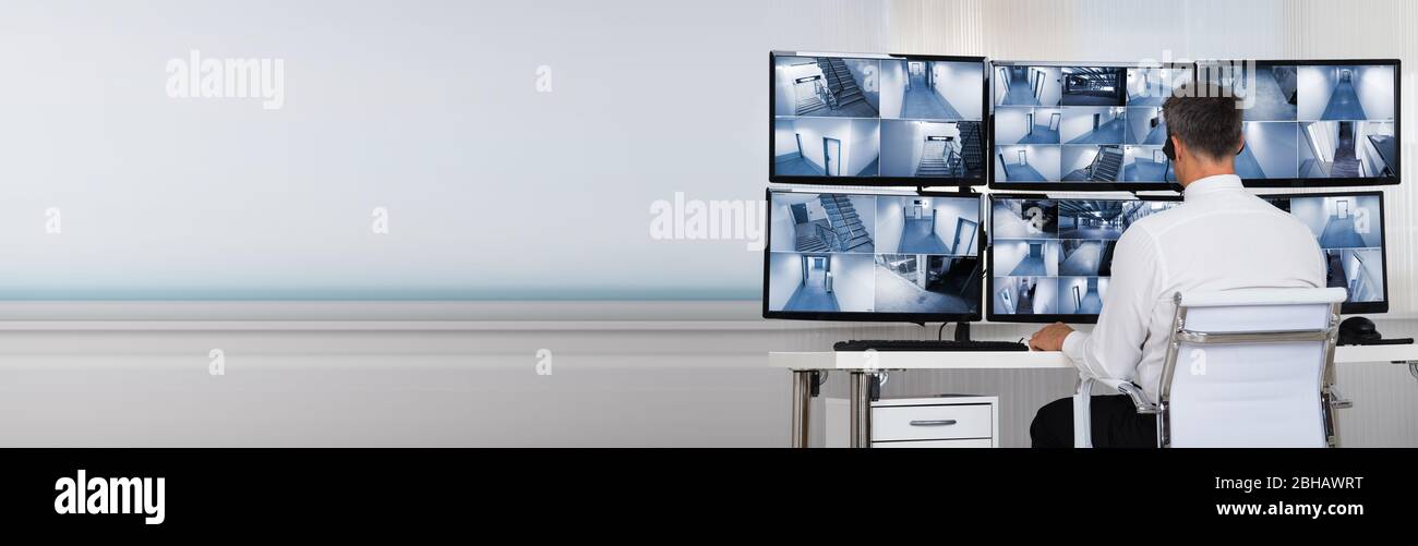 Sicherheitsbediener, der sich CCTV-Kamerabilder auf dem Computer ansieht Stockfoto