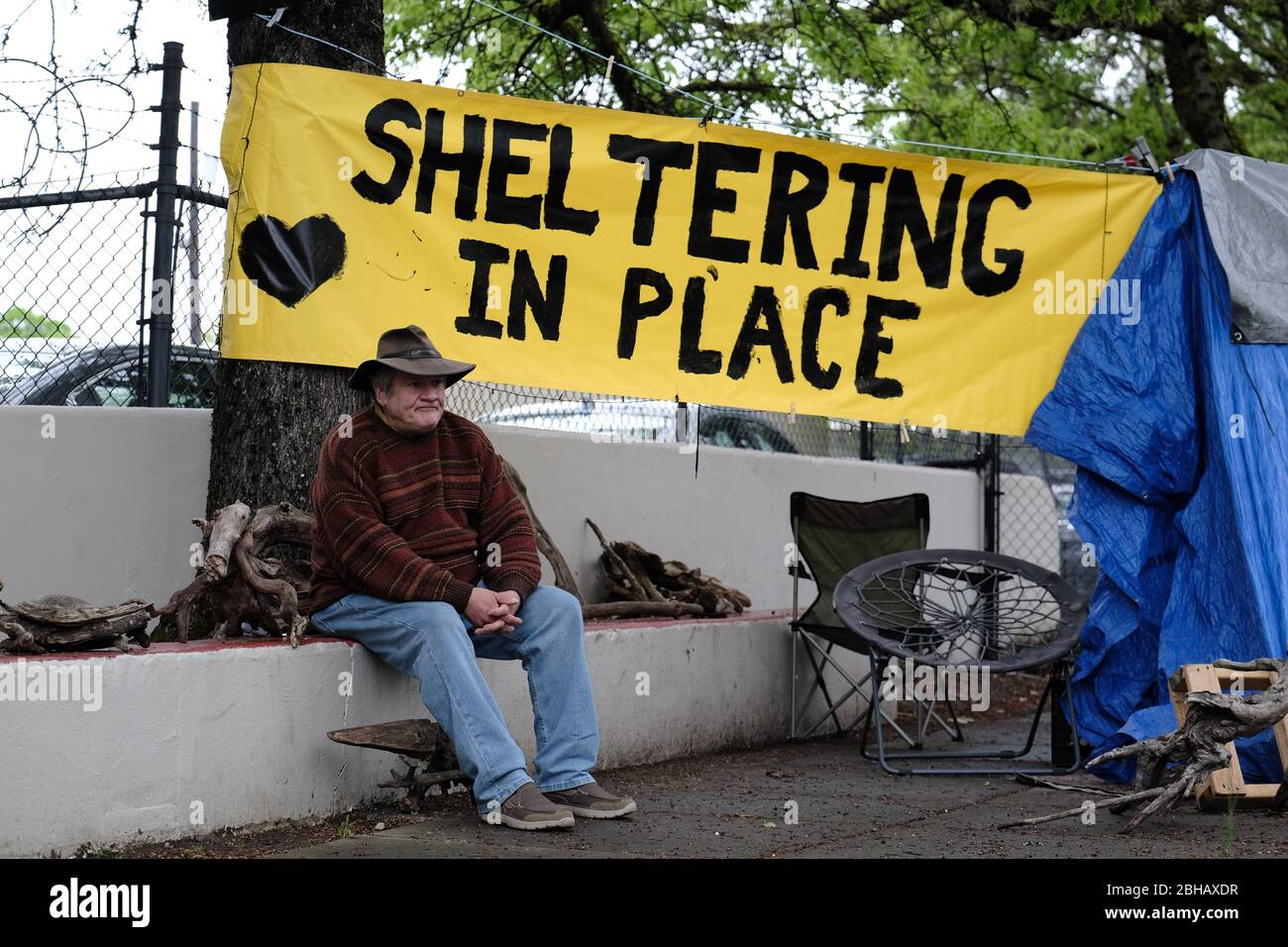 Portland, USA. April 2020. Jeff Liddicoat sitzt am 24. April 2020 vor dem Campingplatz, den er in der East Burnside Street in Portland, Oregon, zu Hause nennt. Jeff, der seit fast 8 Jahren auf den Straßen der Gegend lebt, hat eine Handwaschstation vor seinem Zelt, die die Gemeinde dank der lokalen Interessengruppe Stop the Sweeps PDX benutzen kann. (Foto: Alex Milan Tracy/Sipa USA) Quelle: SIPA USA/Alamy Live News Stockfoto