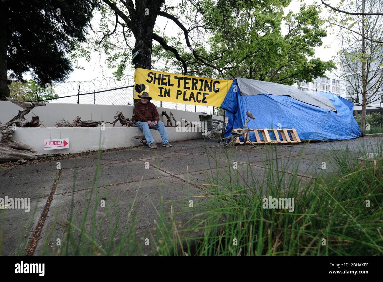 Portland, USA. April 2020. Jeff Liddicoat sitzt am 24. April 2020 vor dem Campingplatz, den er in der East Burnside Street in Portland, Oregon, zu Hause nennt. Jeff, der seit fast 8 Jahren auf den Straßen der Gegend lebt, hat eine Handwaschstation vor seinem Zelt, die die Gemeinde dank der lokalen Interessengruppe Stop the Sweeps PDX benutzen kann. (Foto: Alex Milan Tracy/Sipa USA) Quelle: SIPA USA/Alamy Live News Stockfoto