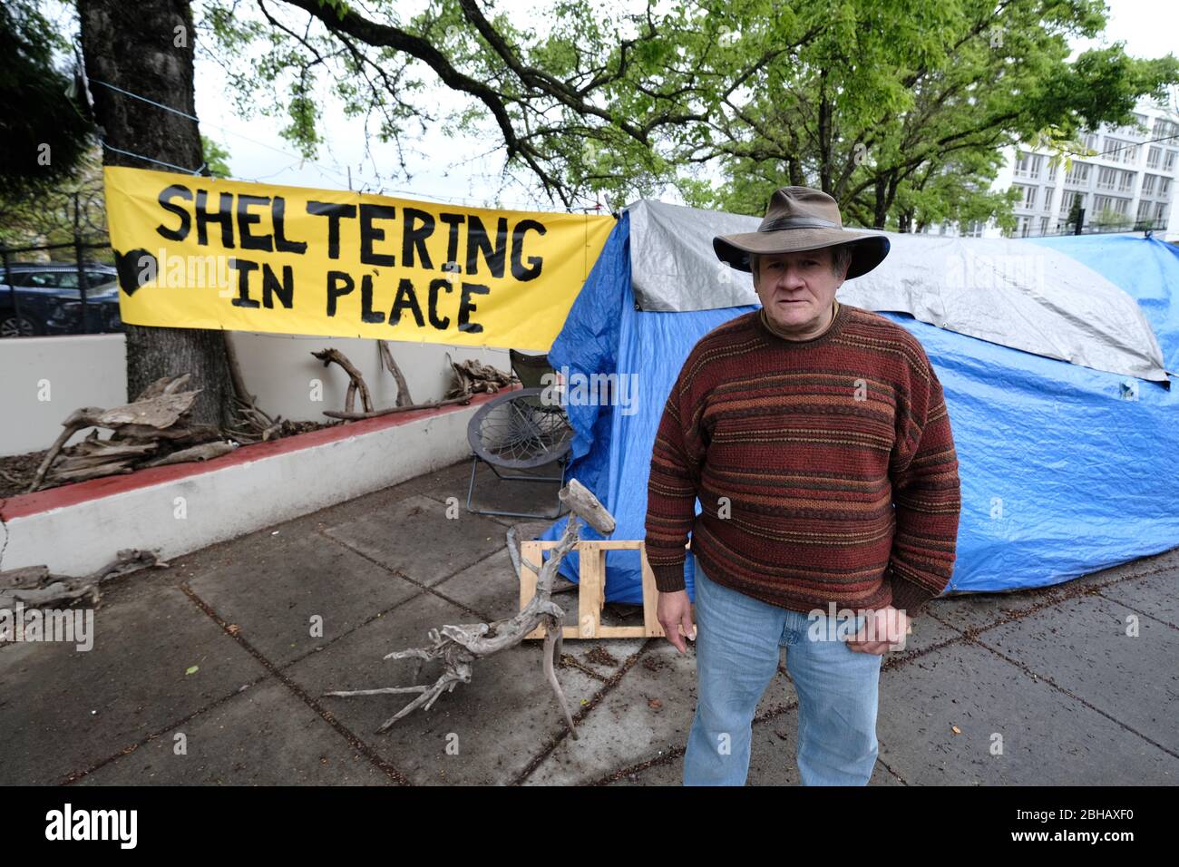 Portland, USA. April 2020. Jeff Liddicoat steht am 24. April 2020 vor dem Campingplatz, den er in der East Burnside Street in Portland, Oregon, zu Hause nennt. Jeff, der seit fast 8 Jahren auf den Straßen der Gegend lebt, hat eine Handwaschstation vor seinem Zelt, die die Gemeinde dank der lokalen Interessengruppe Stop the Sweeps PDX benutzen kann. (Foto: Alex Milan Tracy/Sipa USA) Quelle: SIPA USA/Alamy Live News Stockfoto