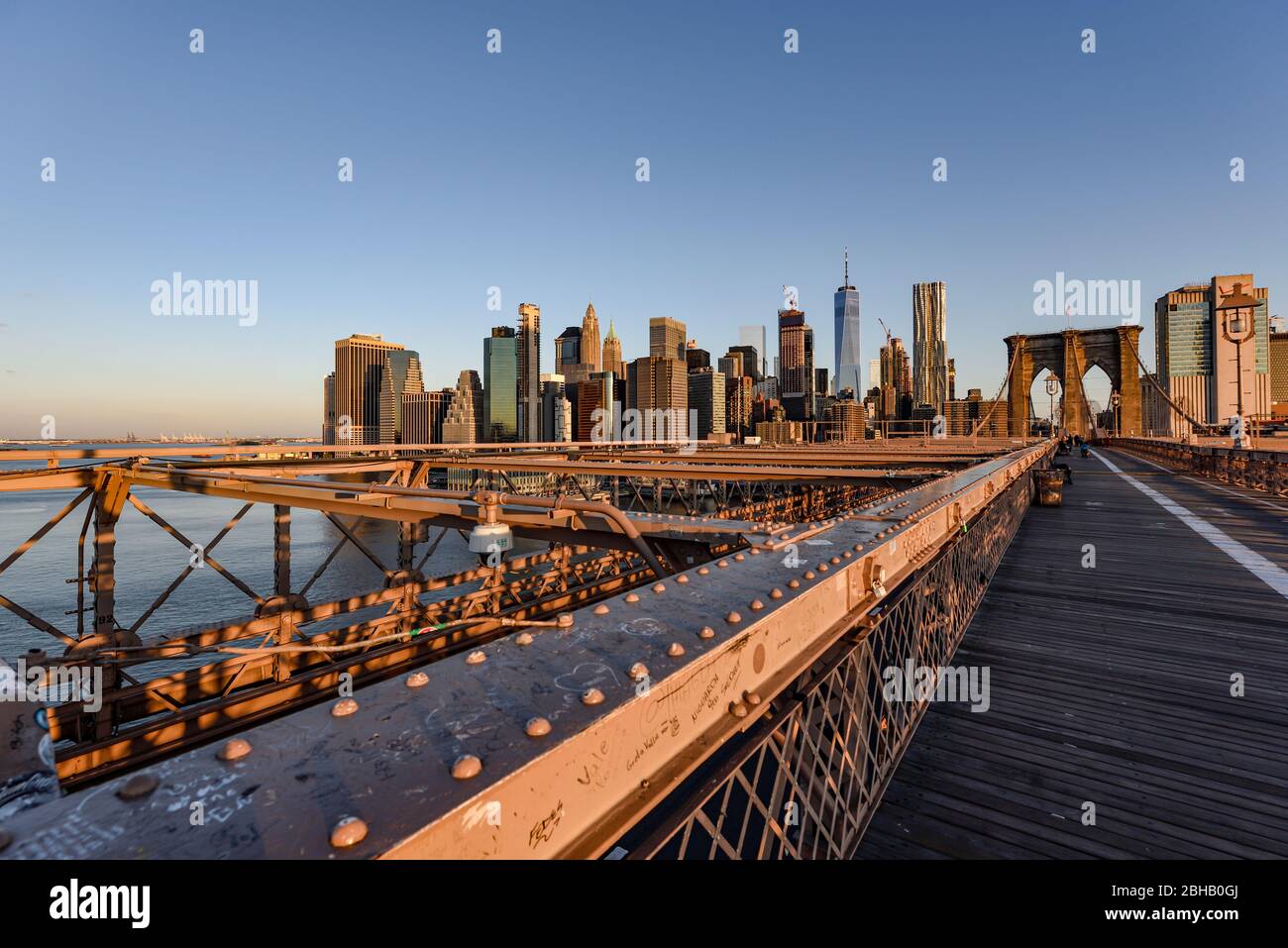 Blick über die verlassene Brooklyn Bridge zur Silhouette der Innenstadt von Manhattan bei Sonnenaufgang im Sommer Stockfoto