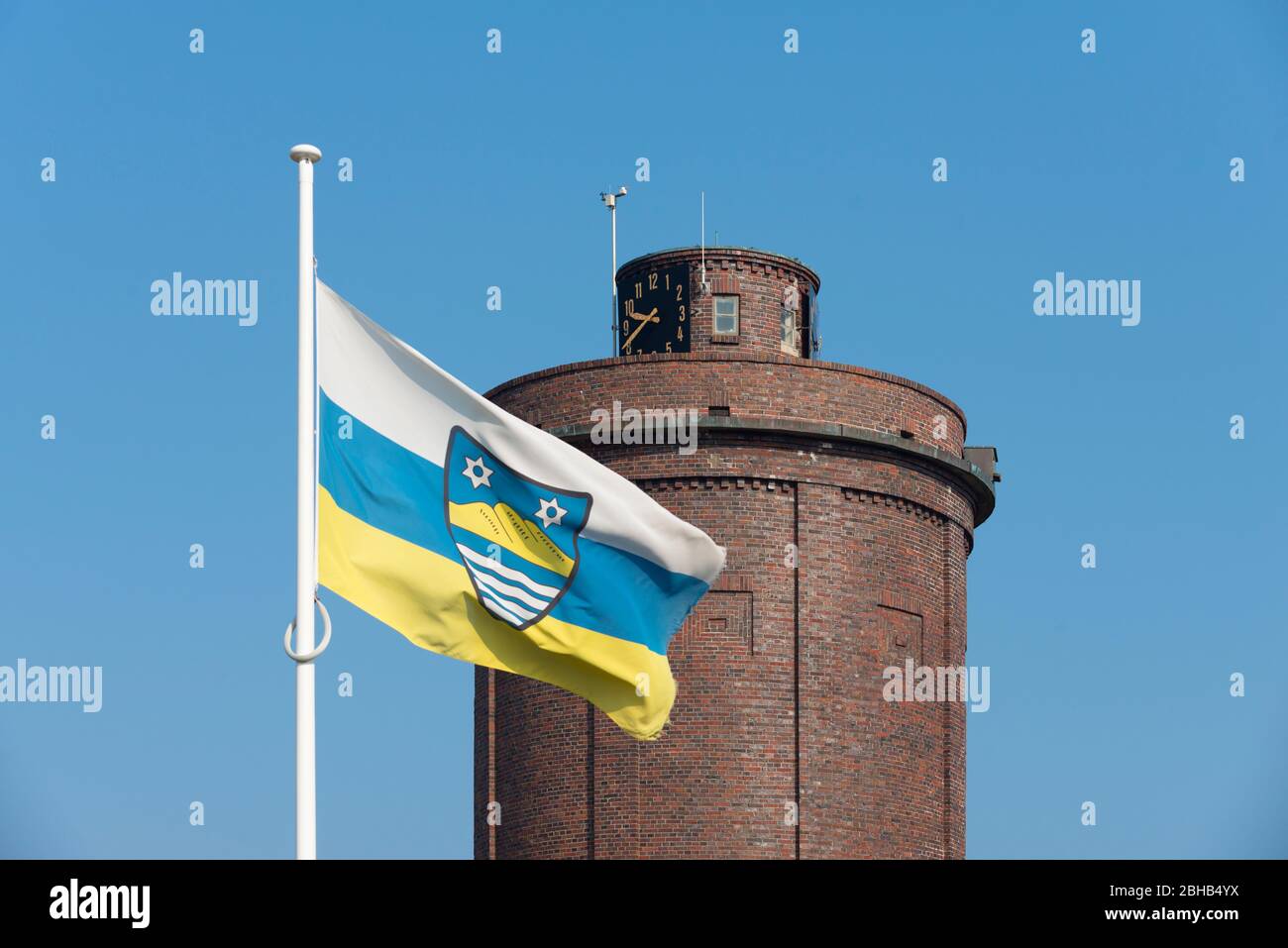 Deutschland, Niedersachsen, Ostfriesland, Juist, Flagge der Insel Juist mit dem Wasserturm 'Doornkaatbuddel' (Spitzname des Turms) im Hintergrund. Stockfoto