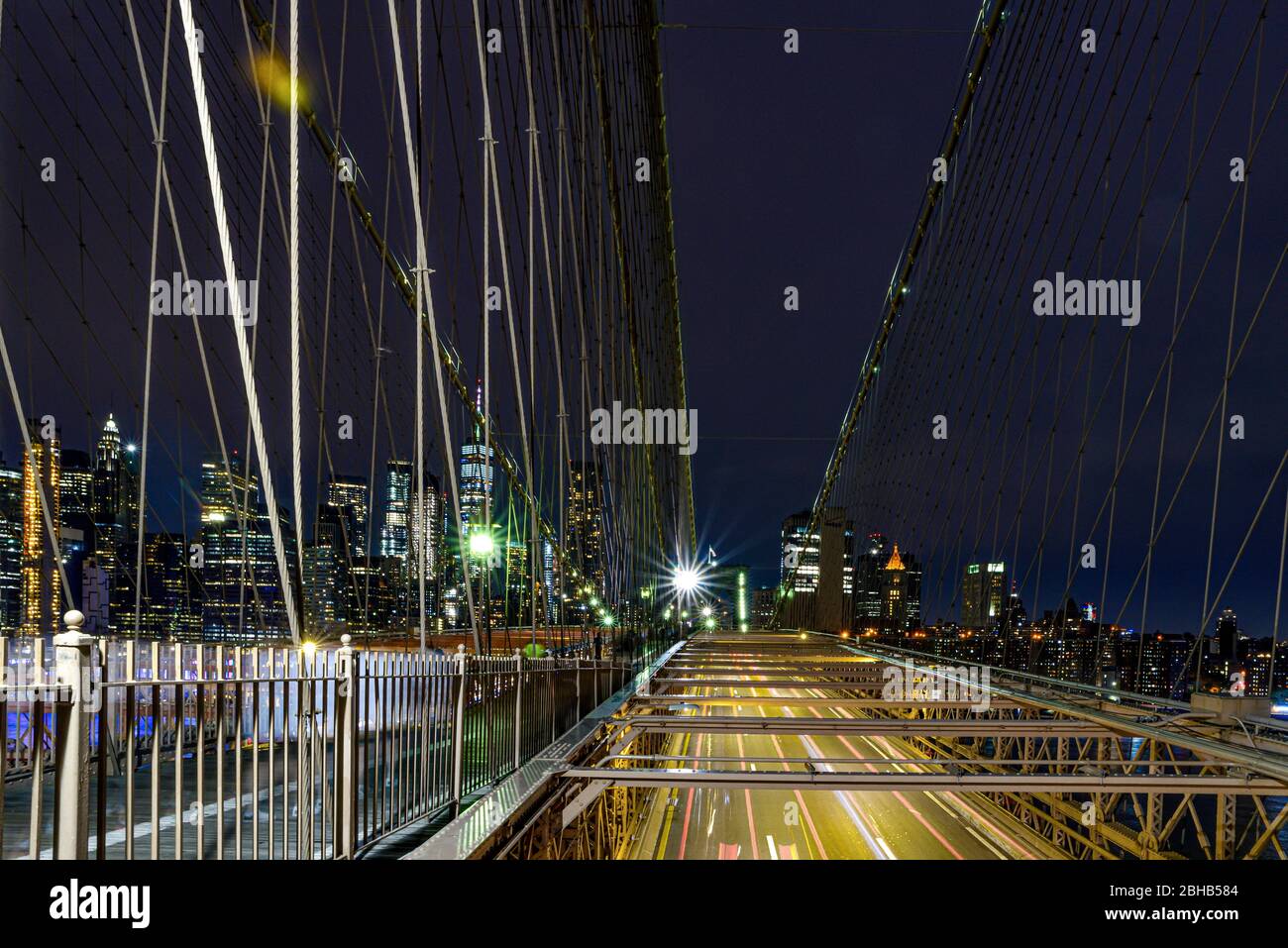 Blick über die nächtliche Brooklyn Bridge zur Skyline von Manhattan, die durch den langen Autoverkehr eingefroren ist Stockfoto
