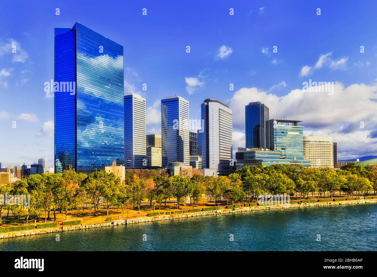Moderne Stadtarchitektur der Innenstadt von Osaka an einem Ufer eines Flusses unter blauem Himmel an einem sonnigen Tag. Stockfoto
