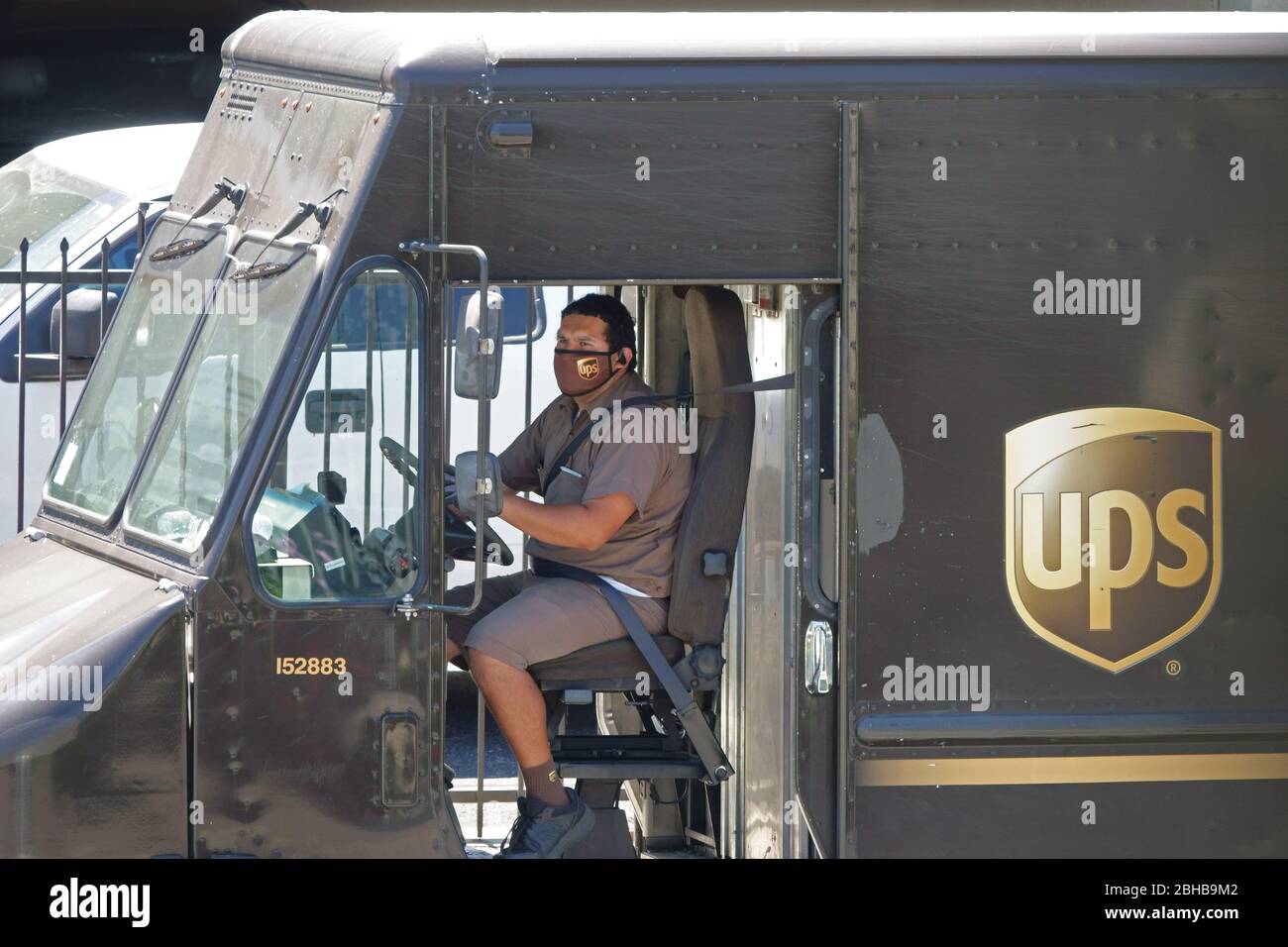 Los Angeles, CA / USA - 24. April 2020: Ein Fahrer für den United Parcel Service UPS trägt eine Firmenlogo-Maske, während er einen Lieferwagen parkt Stockfoto