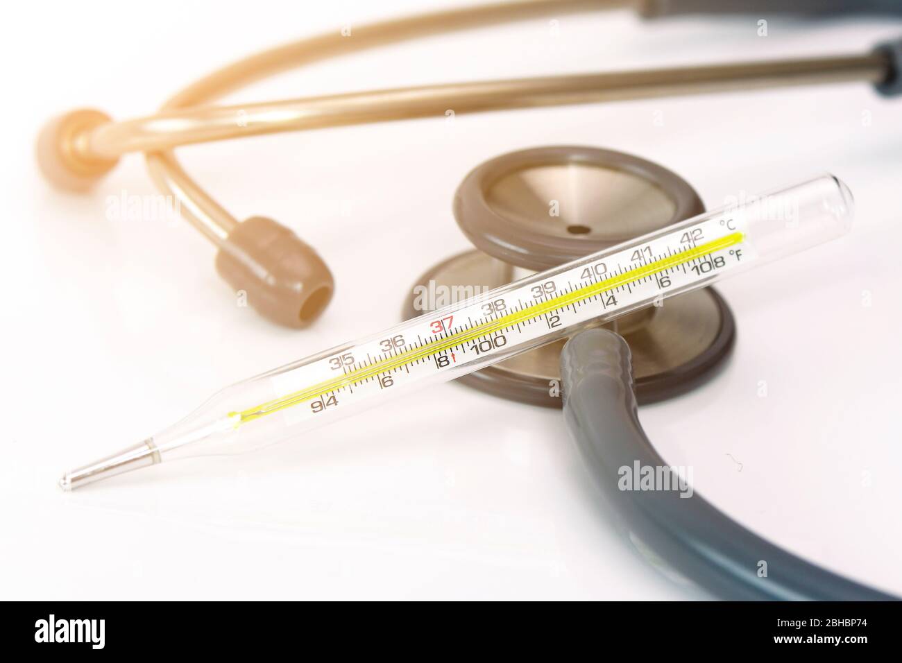 Oral-Thermometer und Stethoskop auf weißem Hintergrund mit warmem Lichtton im Konzept der Früherkennung COVID-19 Infektion mit Körpertemperatur-Messung Stockfoto