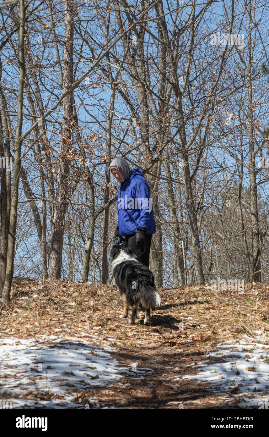 Mann, der im Frühling mit seinem Hund durch den Wald geht Stockfoto