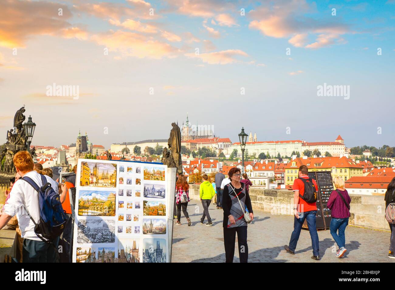 Die St.-Veits-Kathedrale und der Schlosskomplex im Blick, wenn Touristen an Straßenkünstlern und Statuen auf der Karlsbrücke in Prag, Tschechien vorbeikommen. Stockfoto