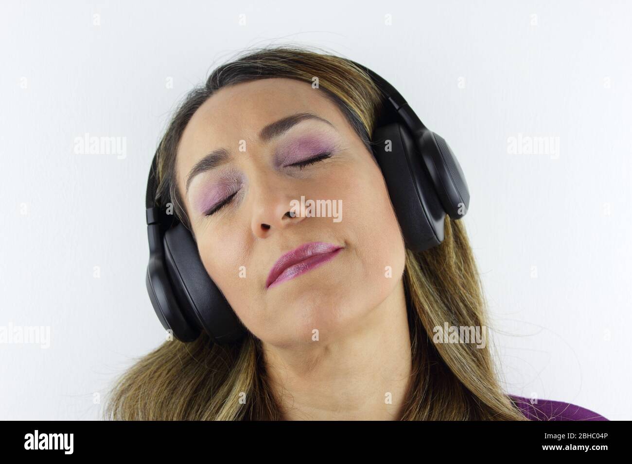 Schöne kolumbianische Frau, die Musik über ihren Kopf Handys Stockfoto