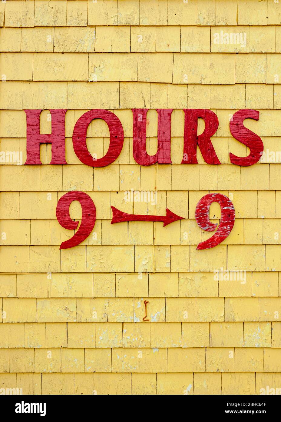 Schild mit Öffnungszeiten auf Seagull's Nest Gift Shop façade. Rot lackierte Buchstaben auf gelb lackiertem Schindelgleis. North Rustico Harbour, PEI, Kanada Stockfoto
