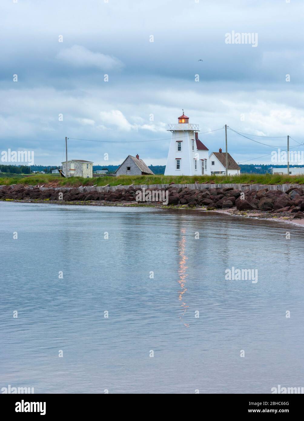 North Rustico Harbour Light - ein aktiver Leuchtturm an der Küste von PEI, Kanada. Riprap entlang der Küste, für Küstenschutz vor schwerer See. Stockfoto