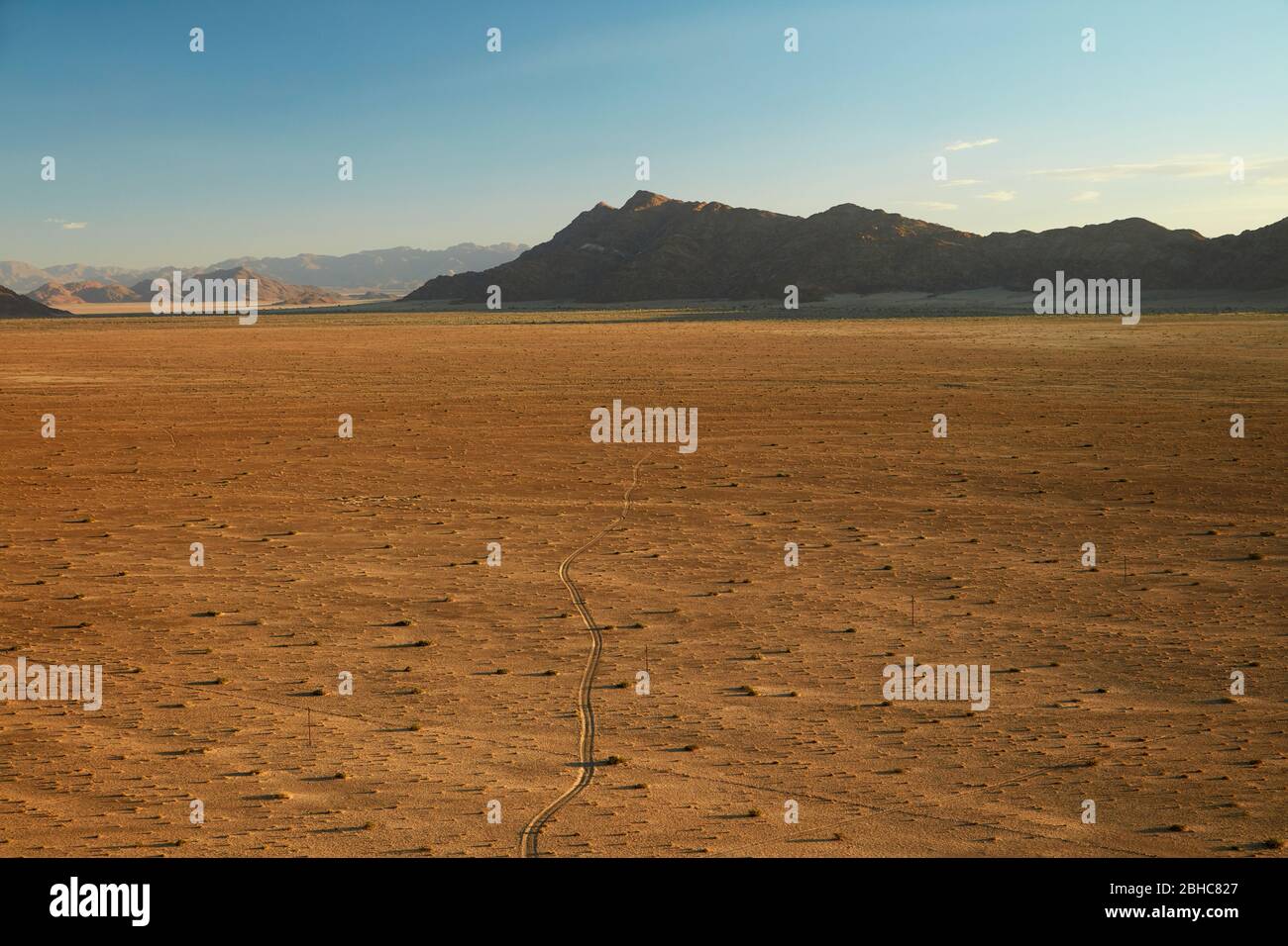 Blick auf die Piste über Ebene und Berge von oben auf einem Felsen Koppie über Desert Camp, Sesriem, Namib Wüste, Namibia, Afrika Stockfoto