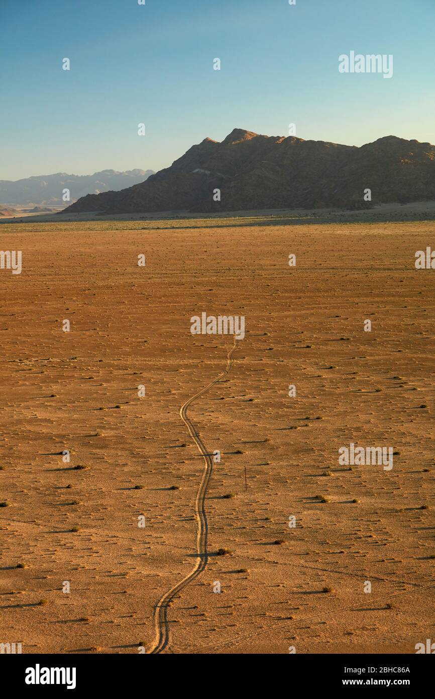 Blick auf die Piste über Ebene und Berge von oben auf einem Felsen Koppie über Desert Camp, Sesriem, Namib Wüste, Namibia, Afrika Stockfoto