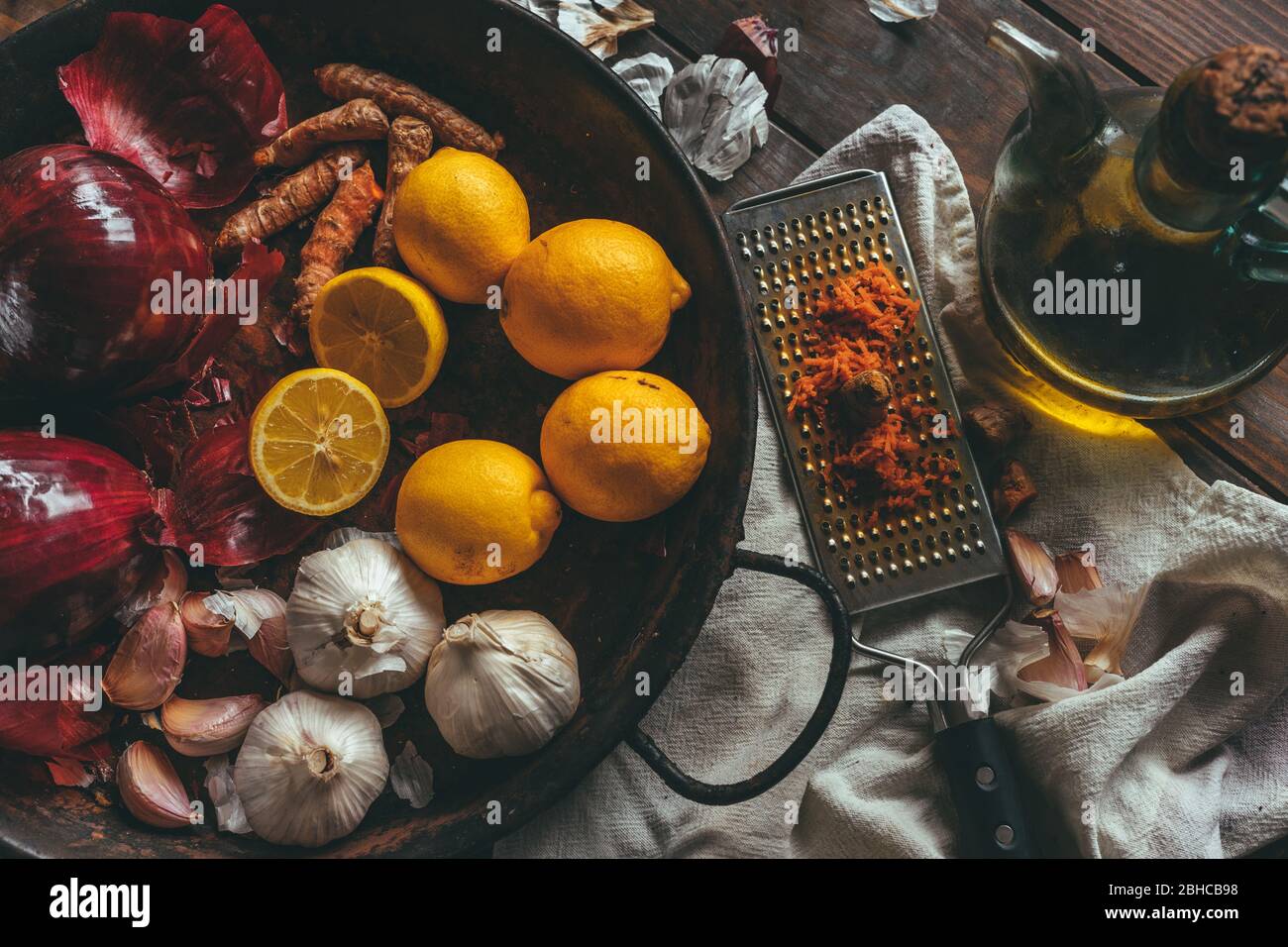 Paella mit Zwiebel, Knoblauch, Olivenöl, Zitrone und geriebenem Kurkuma auf einem rustikalen Holztisch Stockfoto