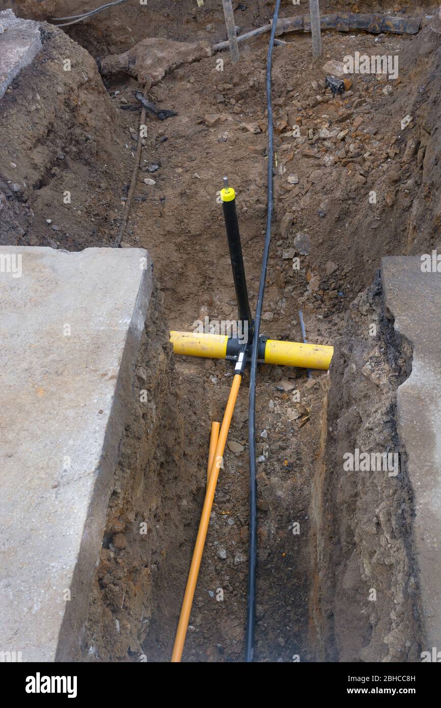 Arbeiten an der Installation von Engineering- und Heizsystemen. Zwei Kunststoffrohre, eine gelbe für Gasleitung und eine schwarze für Stromleitungen. Sie befinden sich in einer SA Stockfoto