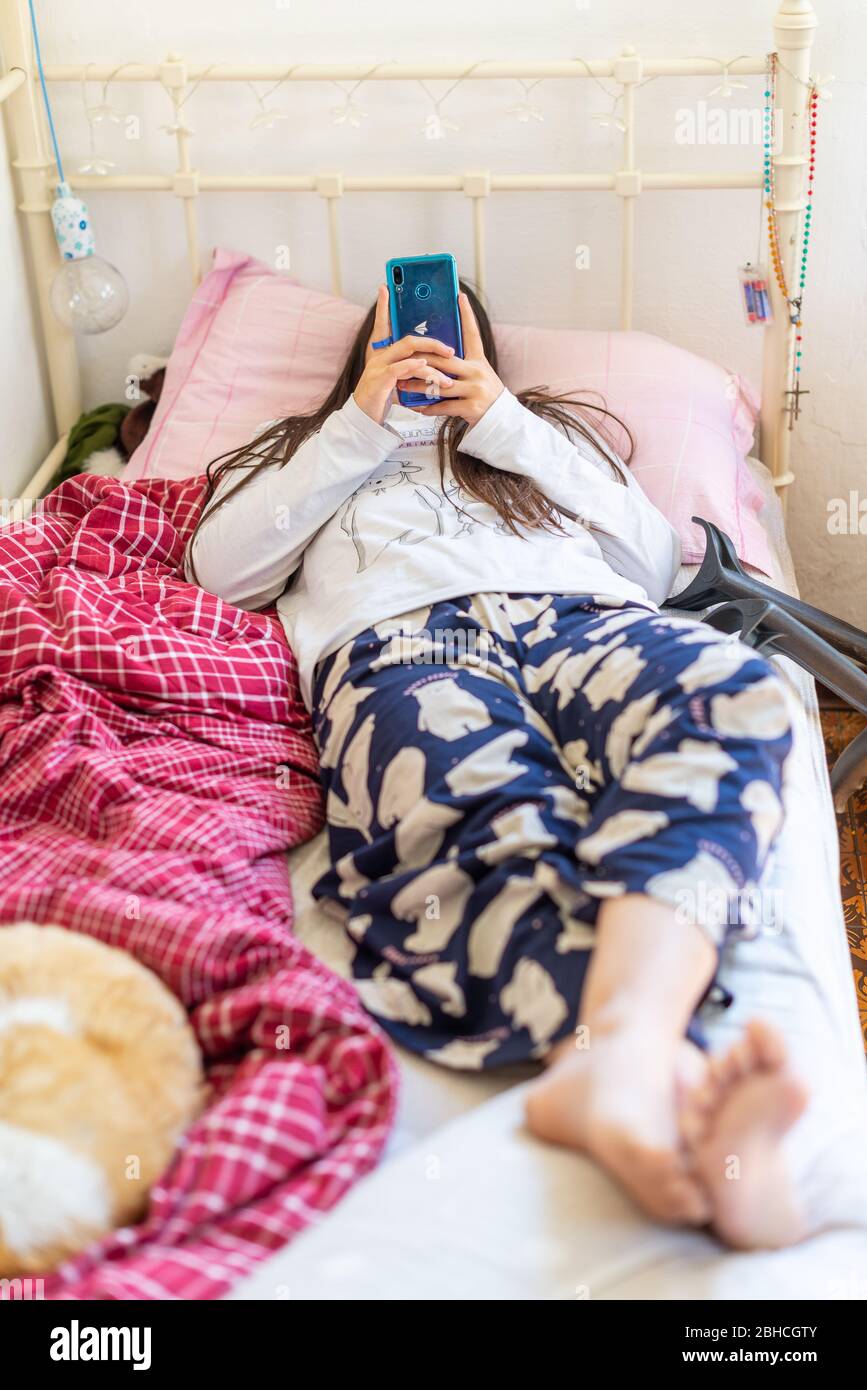 Tennismädchen im Bett mit Smartphone, die Katze im Bett schläft Stockfoto