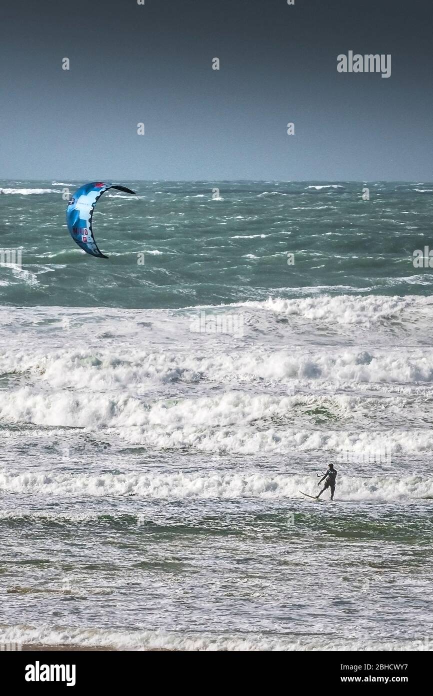Ein einsamer Kitesurfer, der den starken Wind von Storm Jorge in Fistral in Newquay in Cornwall genießt. Stockfoto