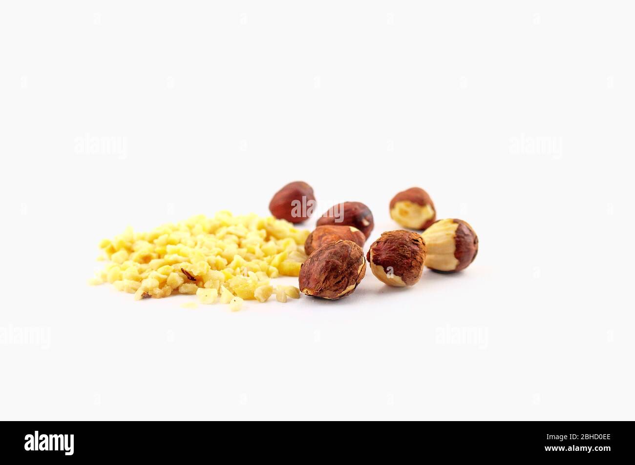 Ein Haufen gehackter Mandeln und ganze Haselnüsse auf weißem Hintergrund isoliert. Stockfoto